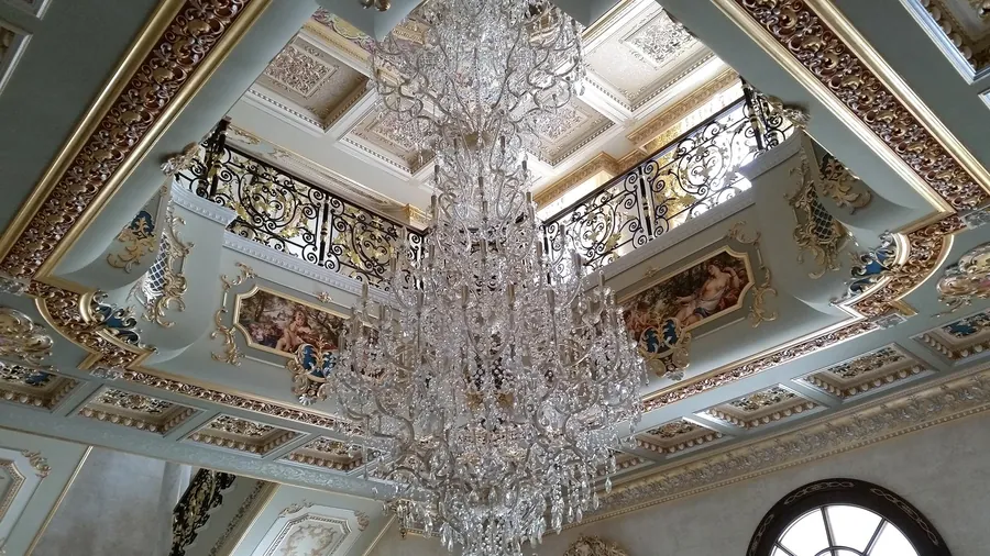 Volta affrescata di una villa privata con lampadario in cristallo visto dal basso.