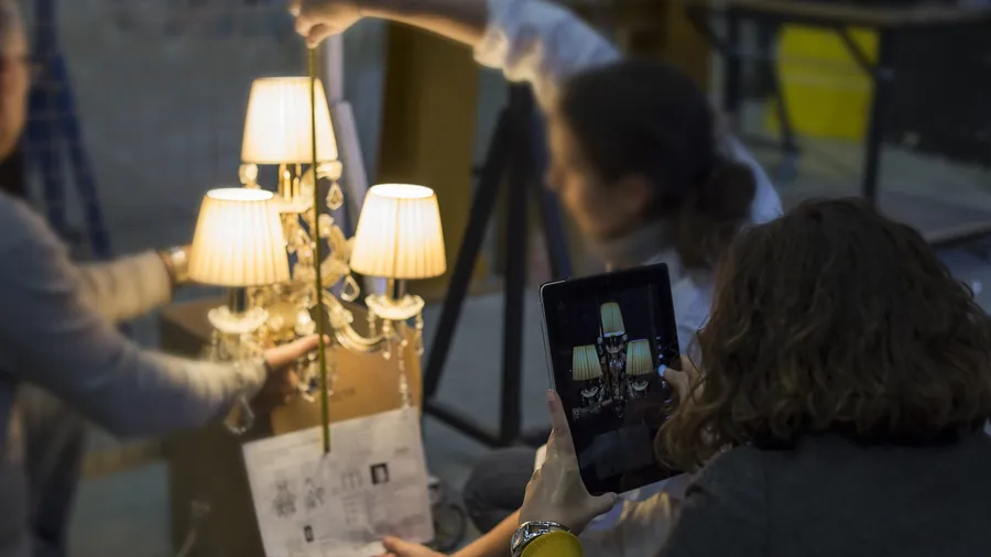 Artigiani verificano le proporzioni di un lampadario acceso.